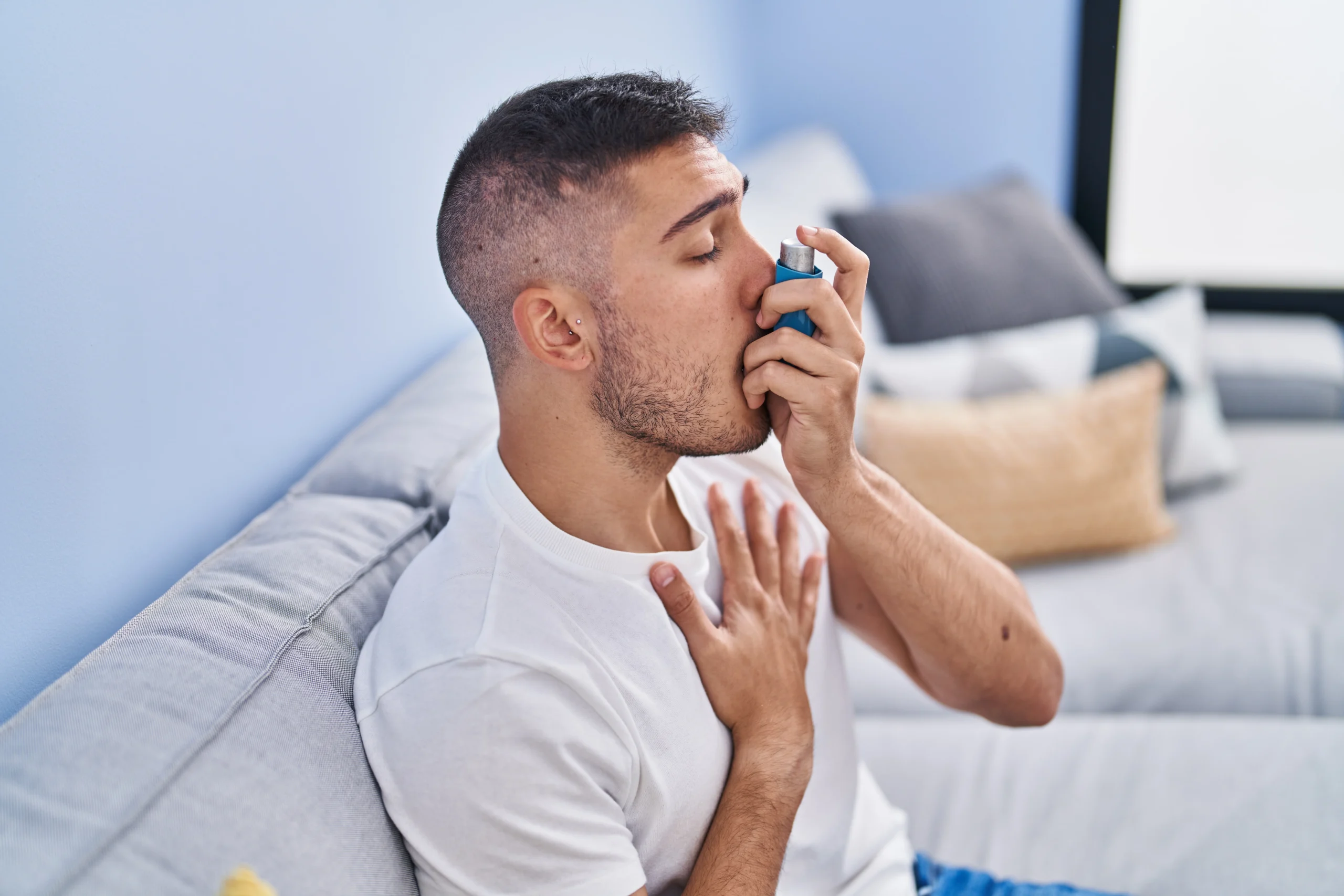 young hispanic man using inhaler sitting sofa home scaled
